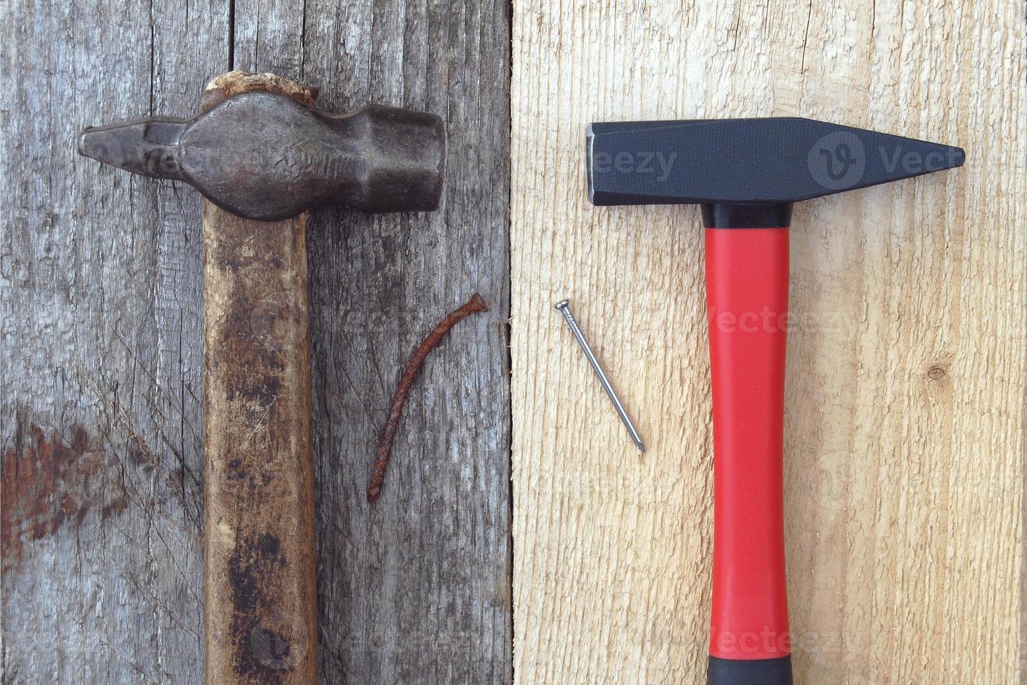 Old hammer, rusty nail vs brand new hammer and new shiny nail on wooden boards photo