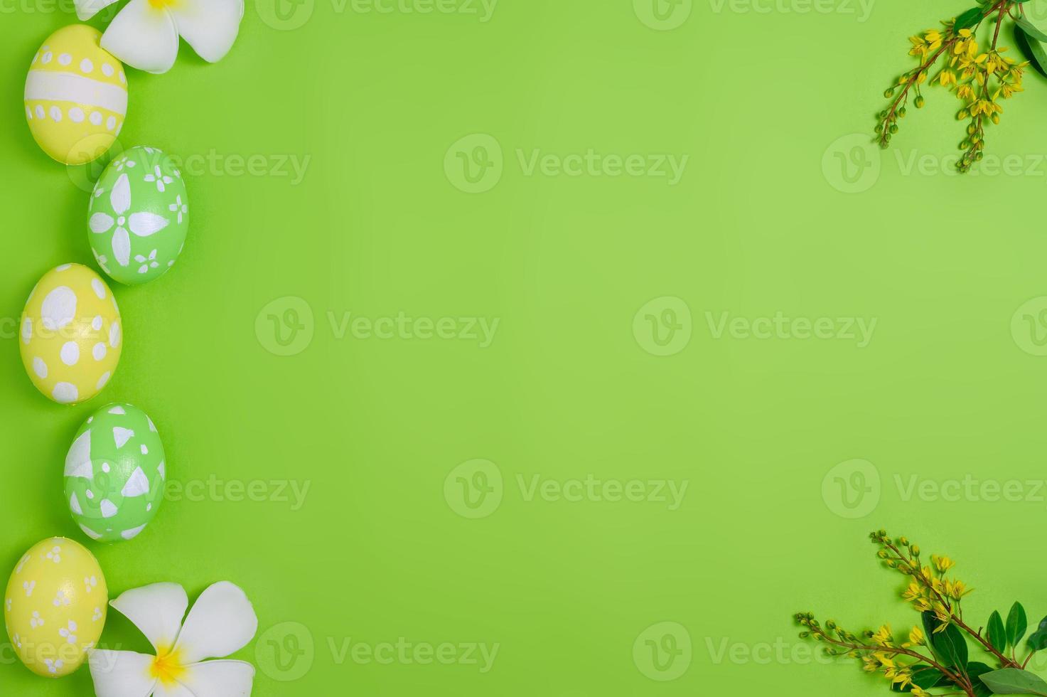 Happy Easter holiday greeting card design concept. Colorful Easter Eggs and spring flowers on pastel green background. Flat lay, top view, copy space. photo