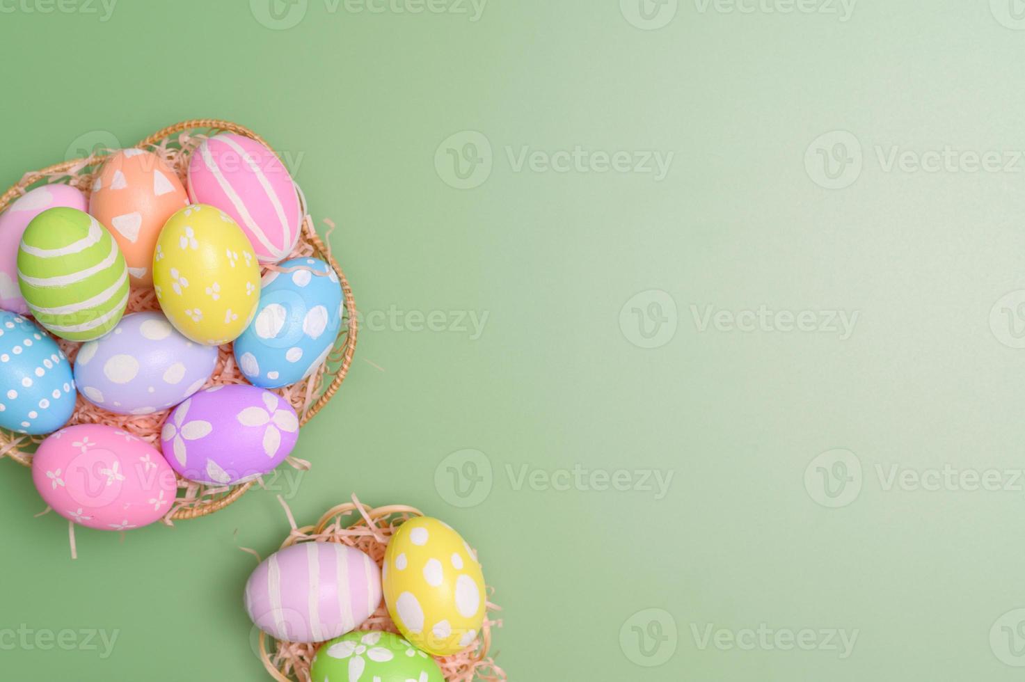 Happy Easter holiday greeting card design concept. Colorful Easter Eggs and spring flowers on pastel green background. Flat lay, top view, copy space. photo