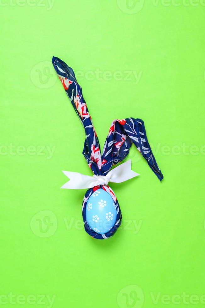 Happy Easter holiday greeting card design concept. Colorful Easter Eggs and spring flowers on pastel green background. Flat lay, top view, copy space. photo