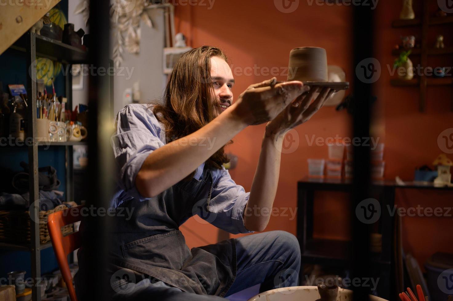 cerámica artista, joven haciendo un pedazo de arcilla moldura tranquilamente y meticulosamente en orden a Produce el más atractivo trabajo posible, foto