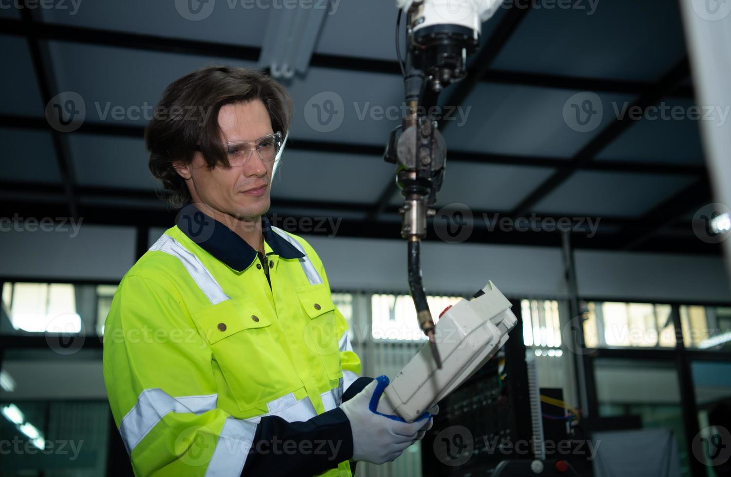 A big welding robot is being inspected and controlled by a robotics engineer. After the machine has been used for the specified amount of time. photo
