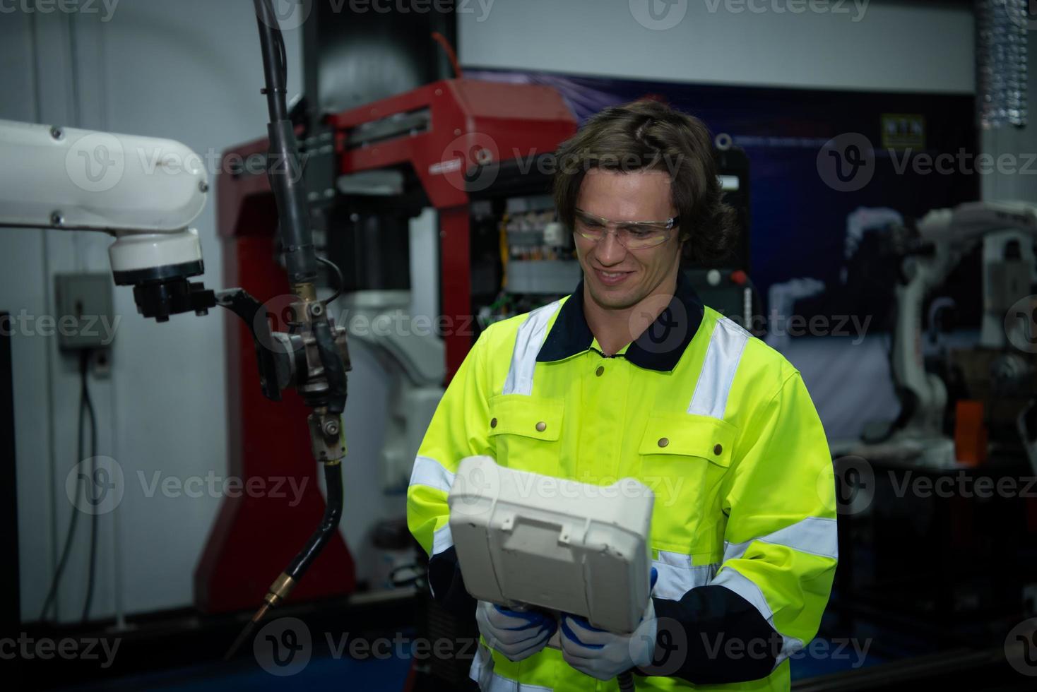 A big welding robot is being inspected and controlled by a robotics engineer. After the machine has been used for the specified amount of time. photo