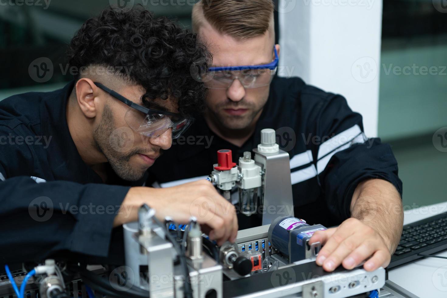 The robotic hand technology teacher is instructing new students on how to use electronic circuit boards and robotic hand commands for a variety of industrial applications. photo