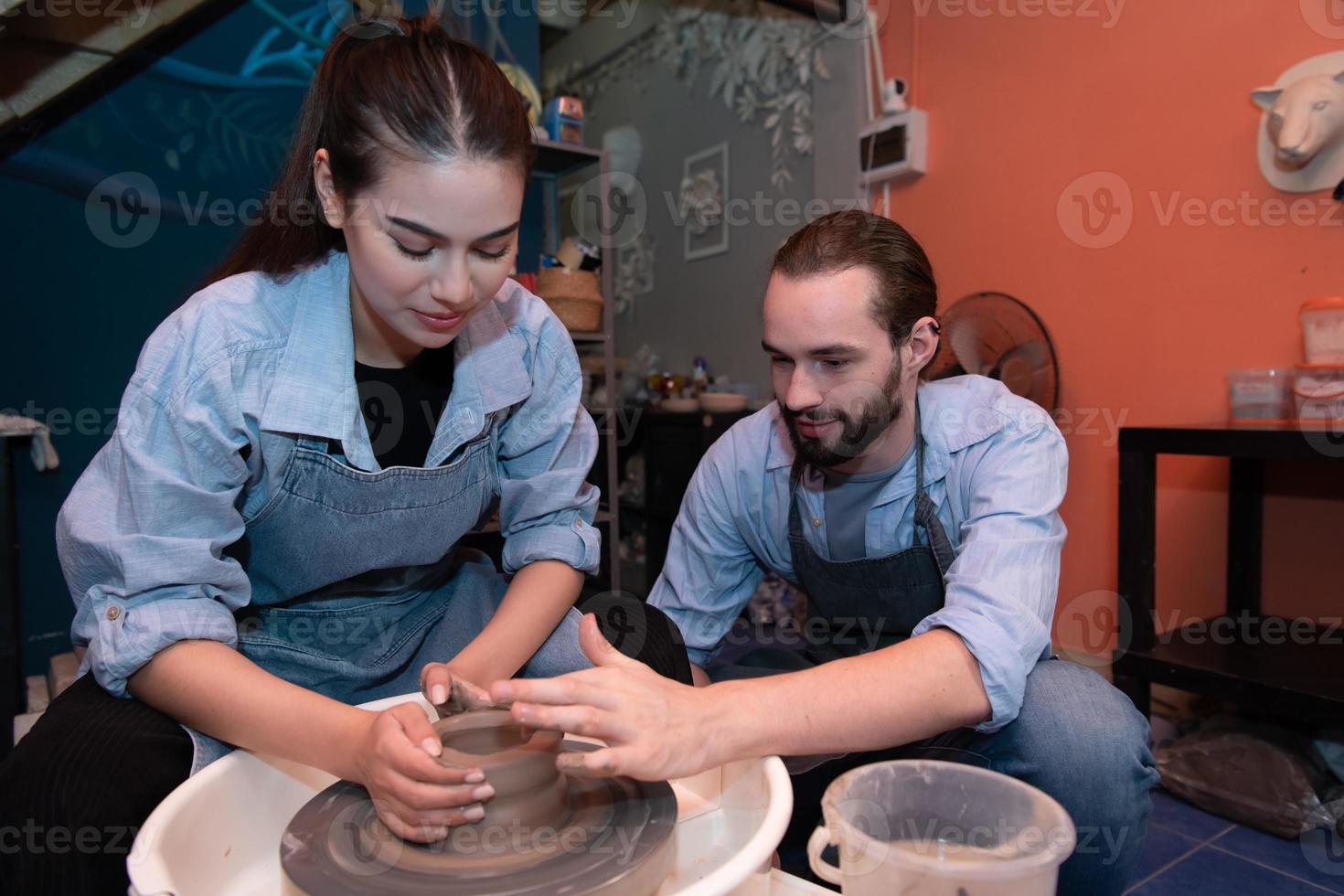 Young couples that enjoy making clay sculptures. Using pottery and assisting one another to create flower vases out of clay photo