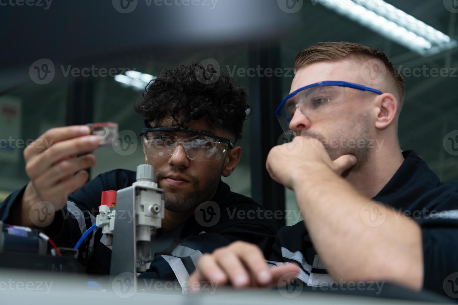 The robotic hand technology teacher is instructing new students on how to use electronic circuit boards and robotic hand commands for a variety of industrial applications. photo