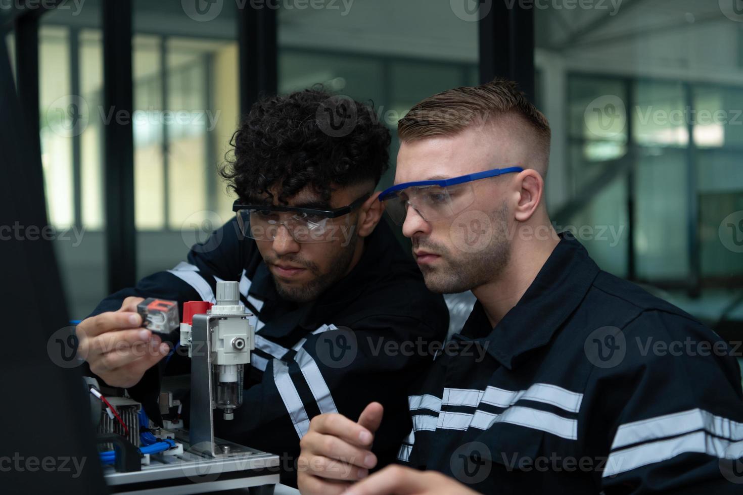 The robotic hand technology teacher is instructing new students on how to use electronic circuit boards and robotic hand commands for a variety of industrial applications. photo
