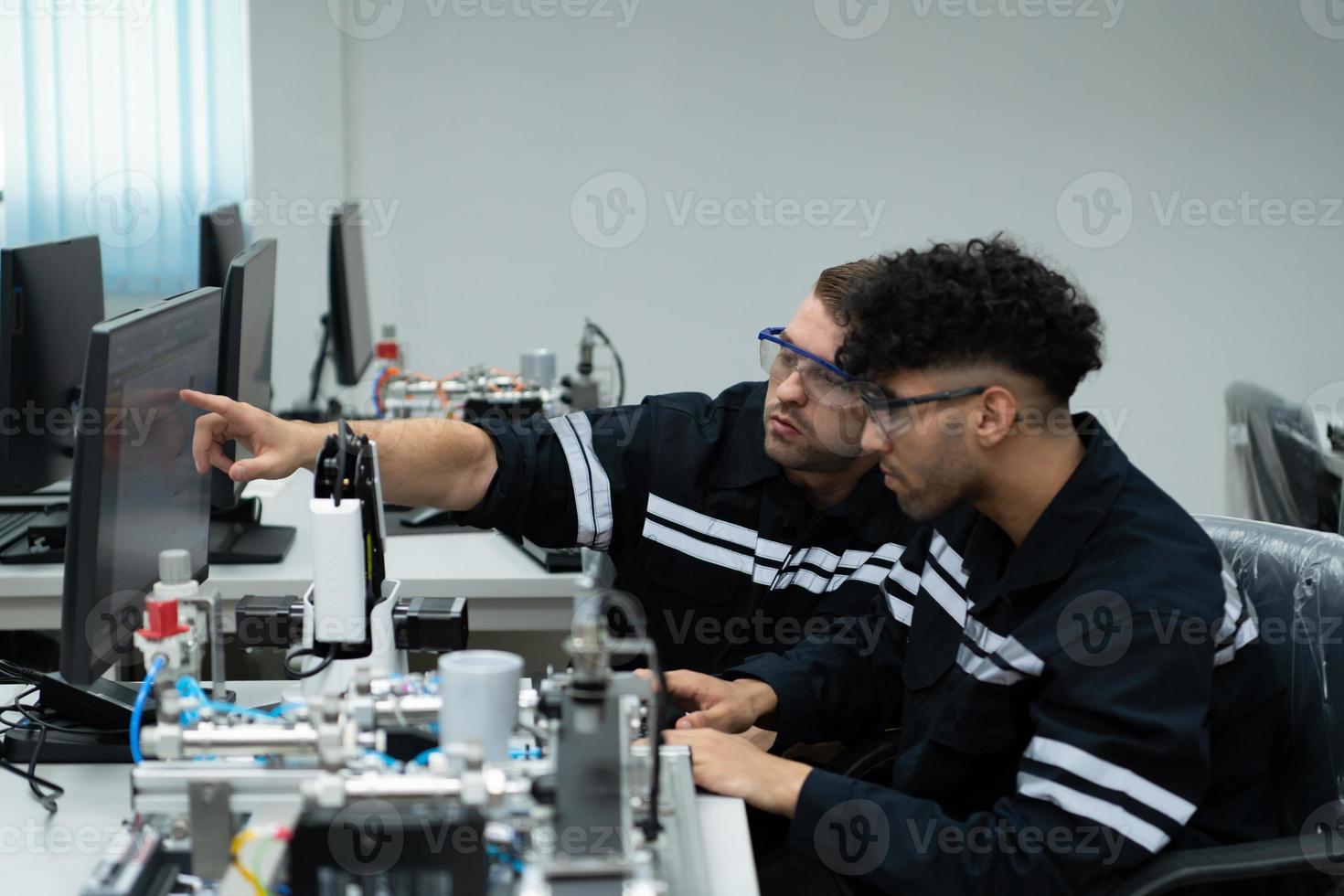 The robotic hand technology teacher is instructing new students on how to use electronic circuit boards and robotic hand commands for a variety of industrial applications. photo