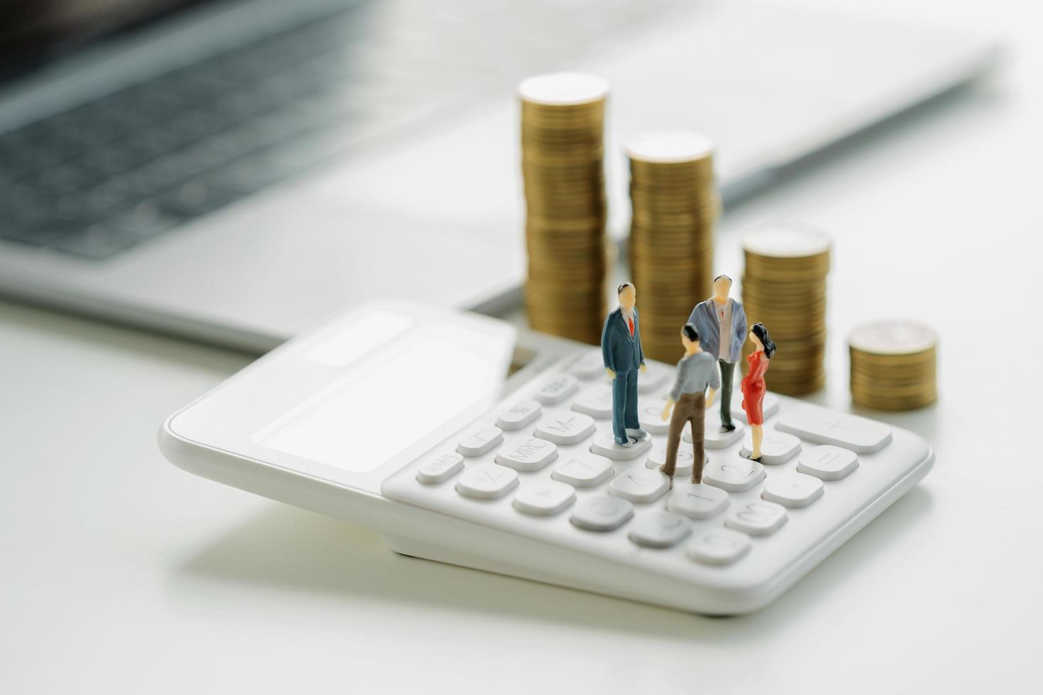 business accounting concept. miniature  toy meeting on calculator with money stack background photo