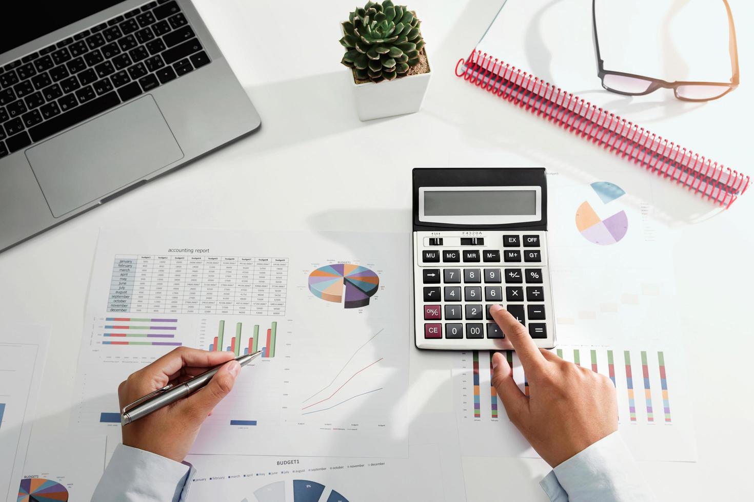 businesswoman working on desk using calculator and laptop analyzing finance accounting in office photo