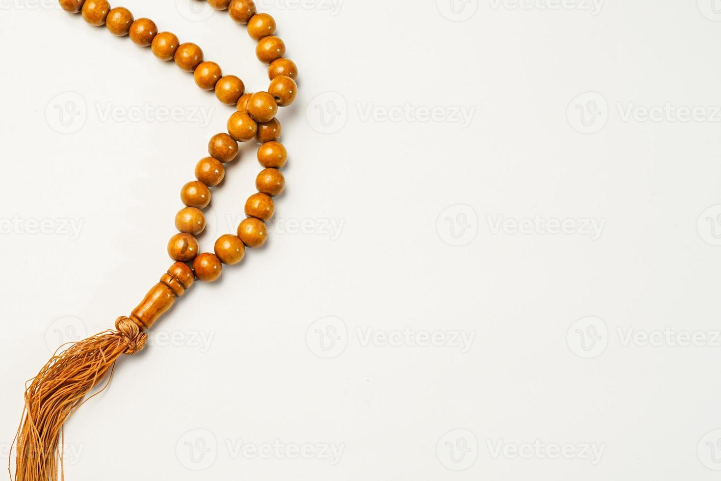 The Holy Al Quran with written arabic calligraphy meaning of Al Quran and rosary beads or tasbih on white background, isolated with copy space. photo