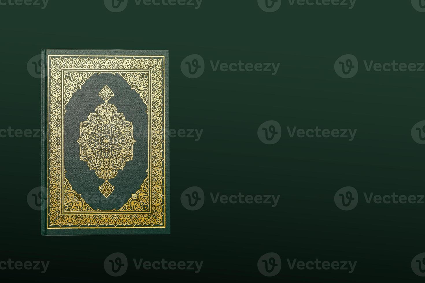The Holy Al Quran with written arabic calligraphy meaning of Al Quran and rosary beads or tasbih on dark green black background with copy space. photo