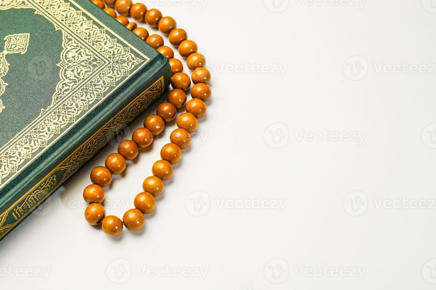 The Holy Al Quran with written arabic calligraphy meaning of Al Quran and rosary beads or tasbih on white background, isolated with copy space. photo