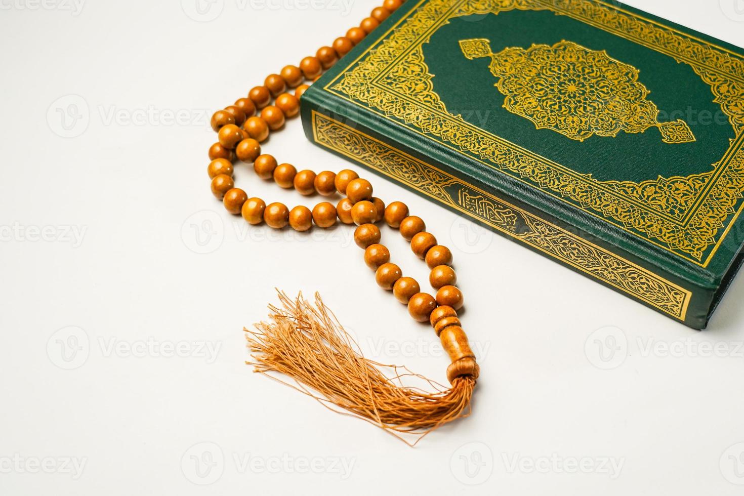 The Holy Al Quran with written arabic calligraphy meaning of Al Quran and rosary beads or tasbih on white background, isolated with copy space. photo