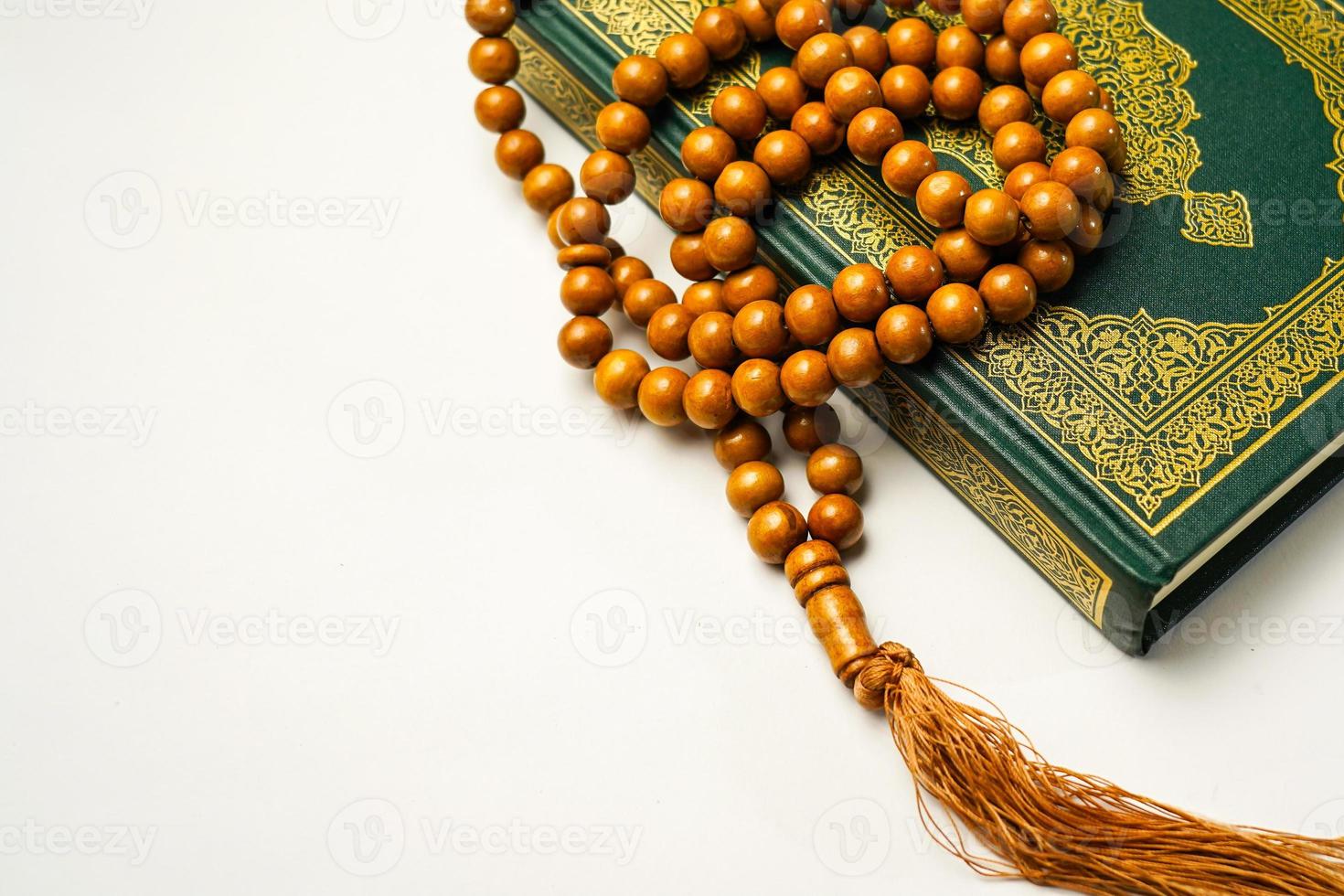 The Holy Al Quran with written arabic calligraphy meaning of Al Quran and rosary beads or tasbih on white background, isolated with copy space. photo