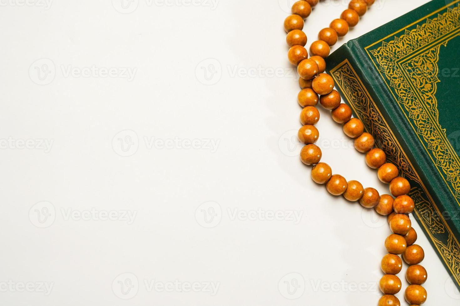 The Holy Al Quran with written arabic calligraphy meaning of Al Quran and rosary beads or tasbih on white background, isolated with copy space. photo