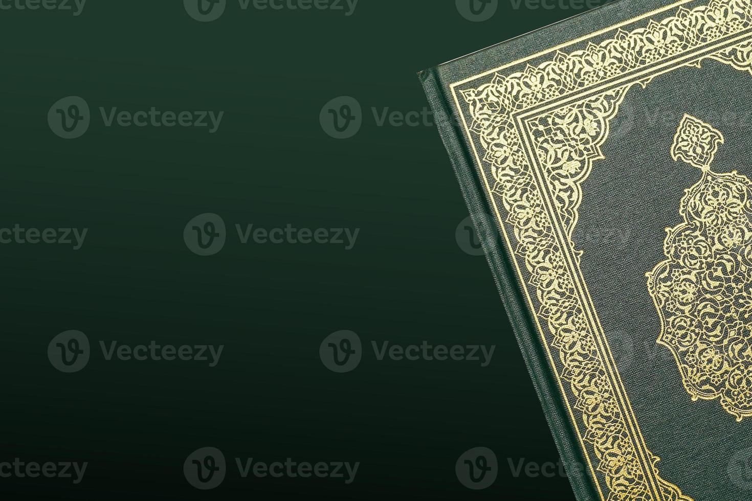 The Holy Al Quran with written arabic calligraphy meaning of Al Quran and rosary beads or tasbih on dark green black background with copy space. photo