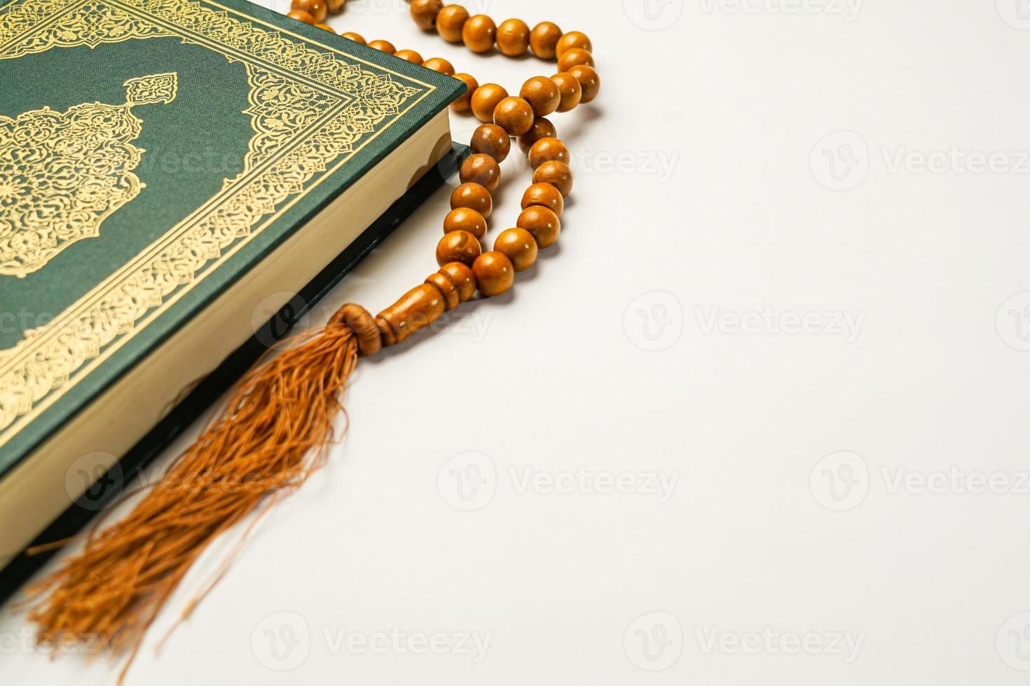 The Holy Al Quran with written arabic calligraphy meaning of Al Quran and rosary beads or tasbih on white background, isolated with copy space. photo