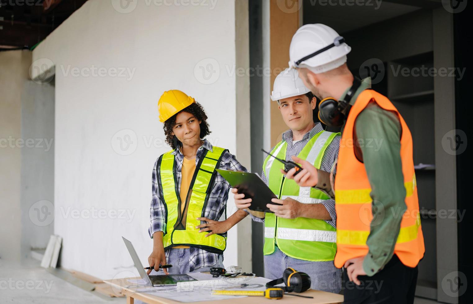 ingenieros son que se discute datos trabajando y ordenador portátil o tableta con arquitectónico proyecto a nuevo construcción sitio en grande proyecto. foto