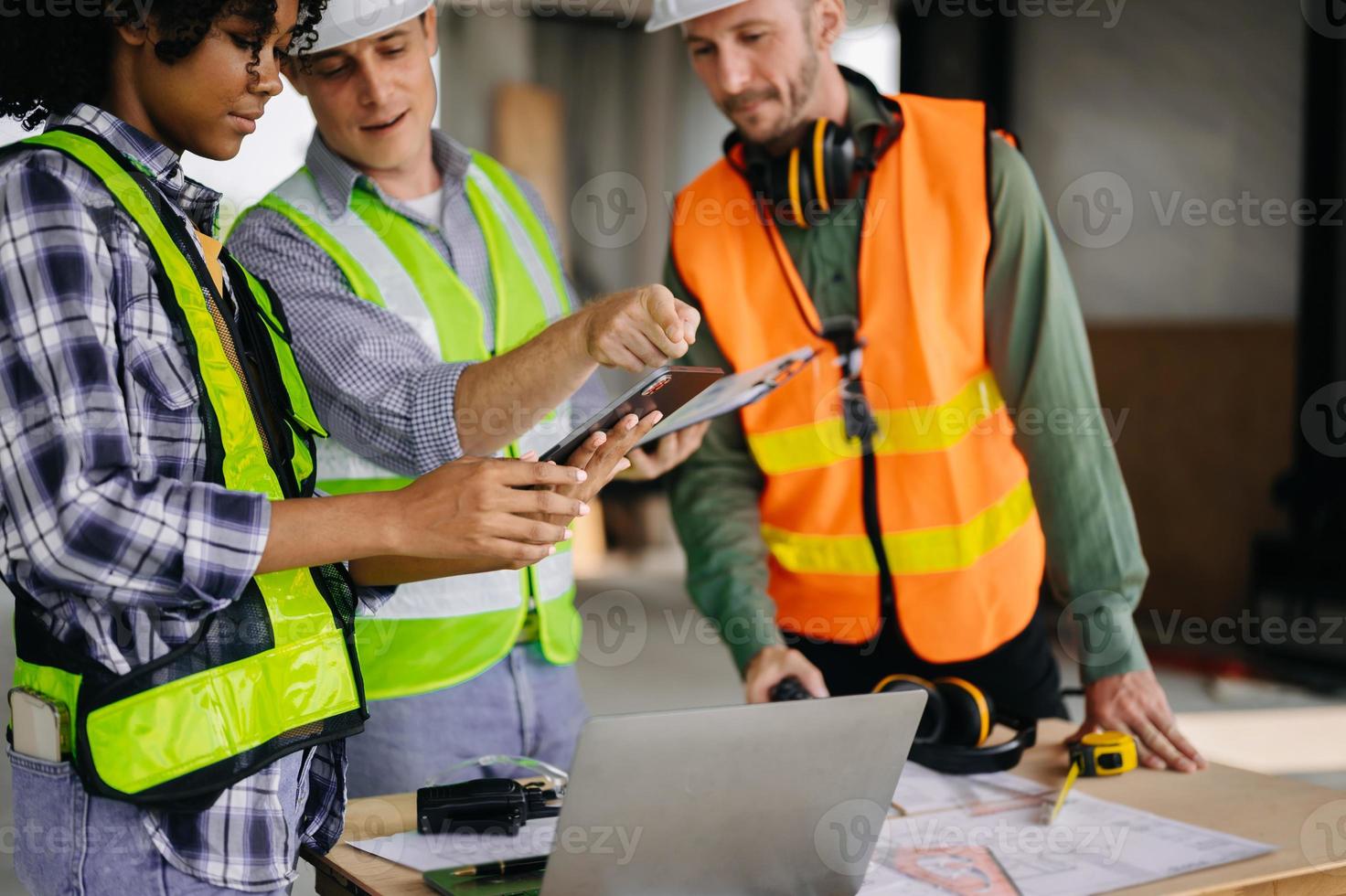 colegas discutiendo el trabajo de datos y la tableta, la computadora portátil con el proyecto arquitectónico en el sitio de construcción en el escritorio de la oficina foto