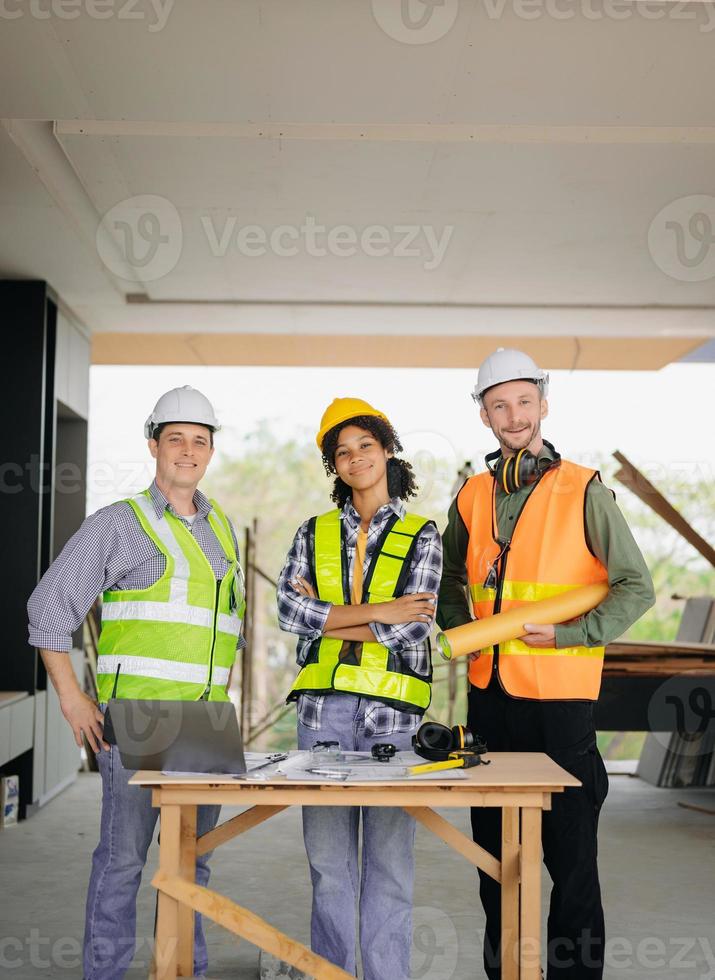 ingenieros son que se discute datos trabajando y ordenador portátil o tableta con arquitectónico proyecto a nuevo construcción sitio en grande proyecto. foto