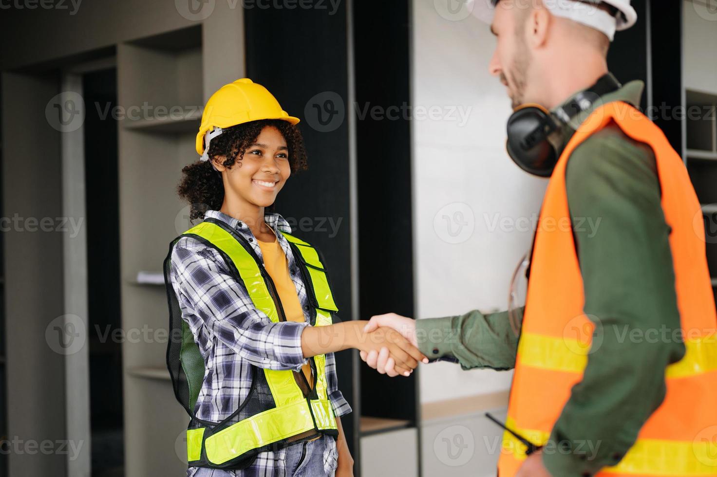 Construction team shake hands greeting start new project plan behind yellow helmet on desk in office center to consults about their building project. photo