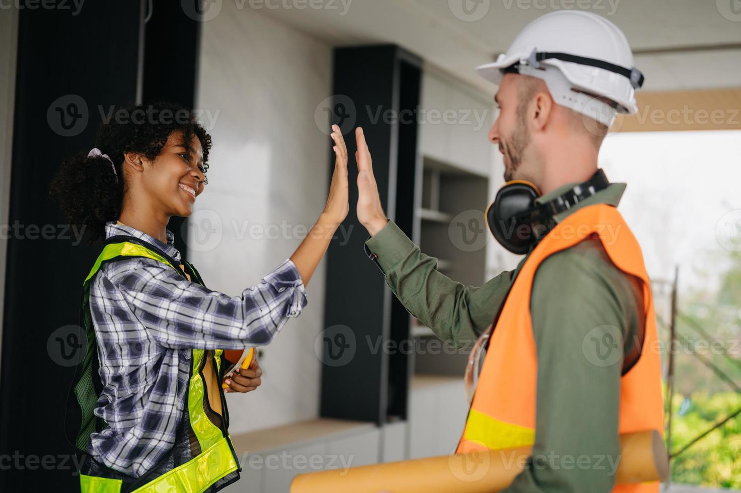 Construction team shake hands greeting start new project plan behind yellow helmet on desk in office center to consults about their building project. photo