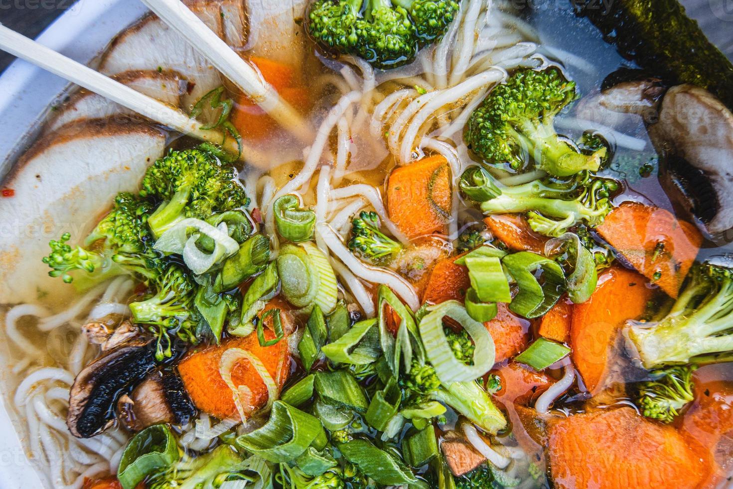 cuenco de ramen con palillos y brócoli en parte superior foto