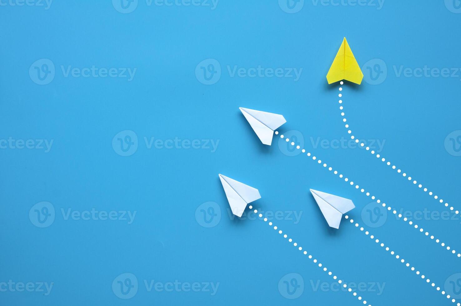 Top view of paper airplane - Yellow paper airplane origami flying to a different direction leaving other white airplanes on blue background. Leadership concept photo