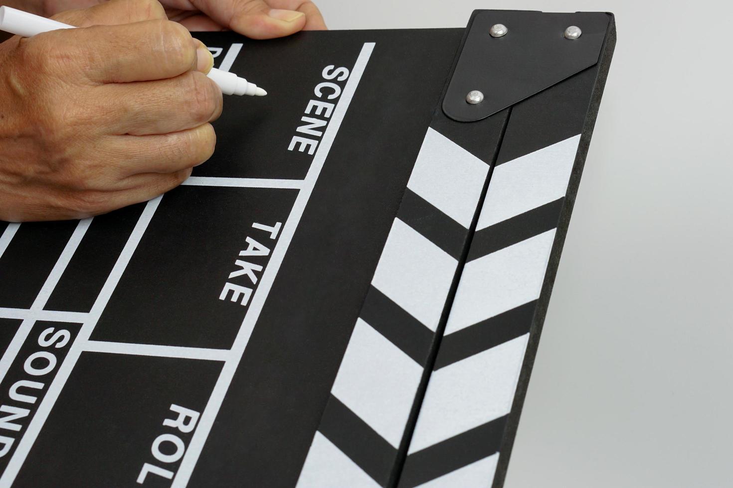 Focus the hand is holding clapperboard or movie slate black color and marker pen. Cinema industry concept. photo