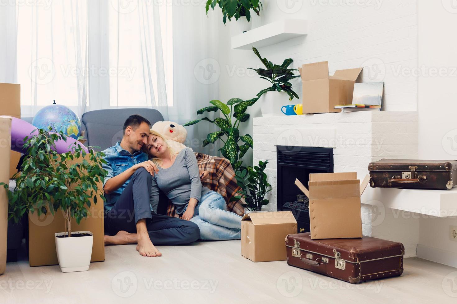 estreno de una casa. joven Pareja en un nuevo casa, departamento. hombre amd mujer sentado junto a cartón cajas foto