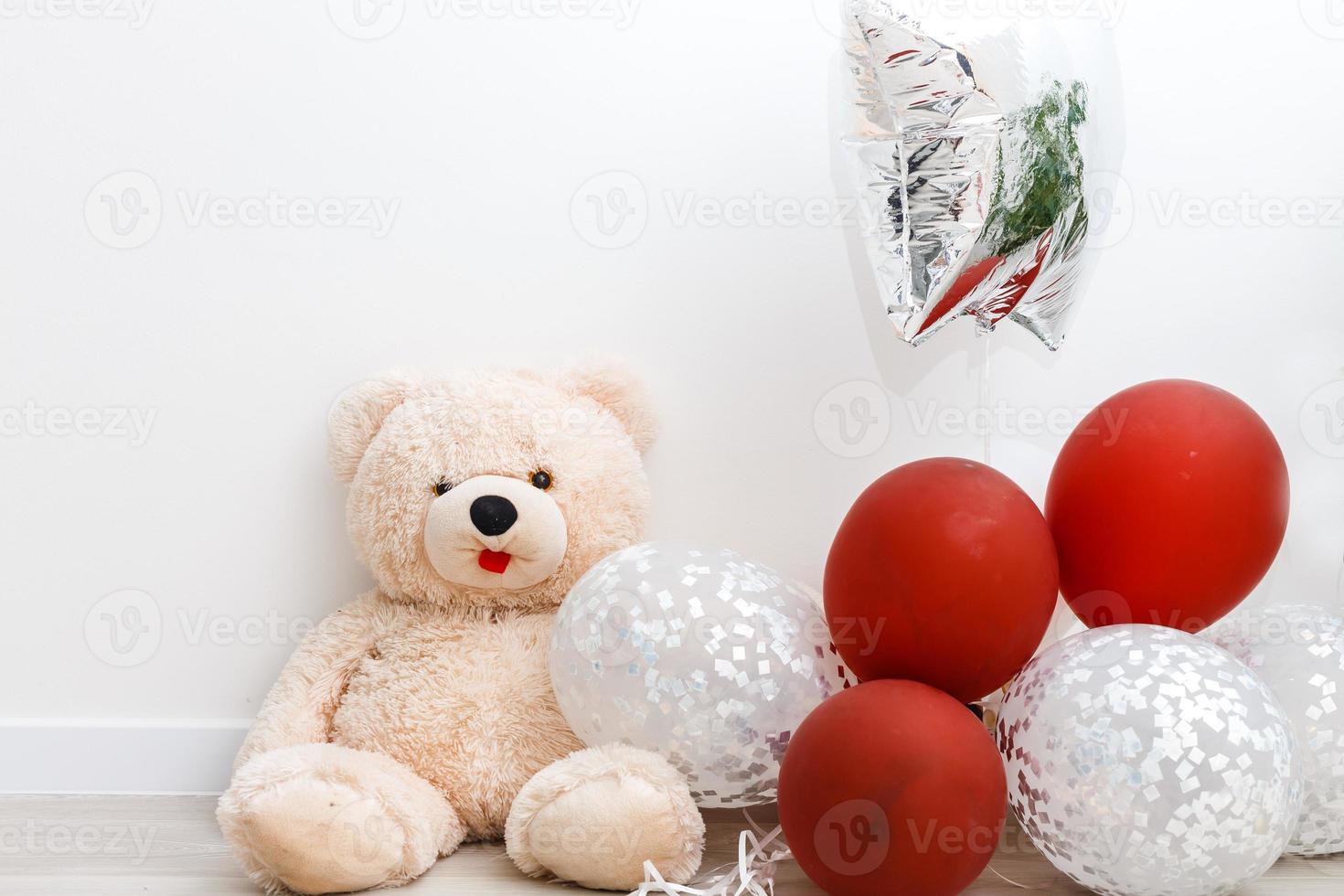 osito de peluche oso con vistoso globos aislado en blanco foto