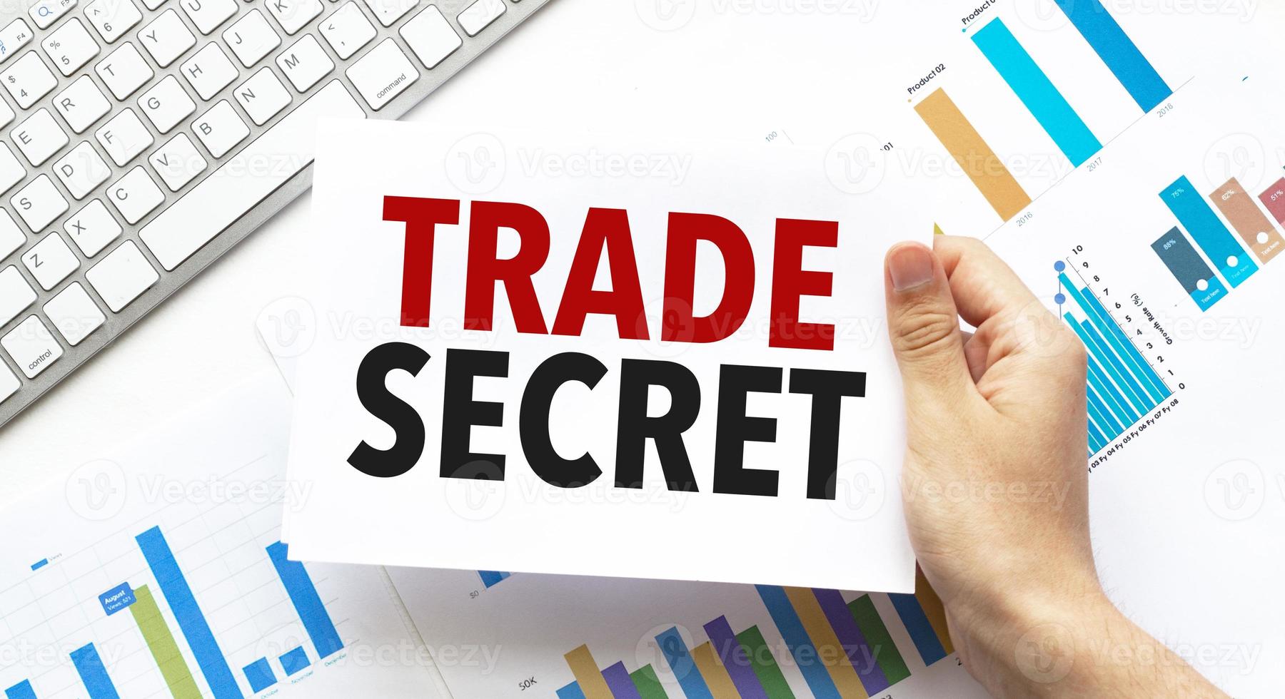 Businessman holding a card with text trade secret .Keyboard, diagram and white background photo