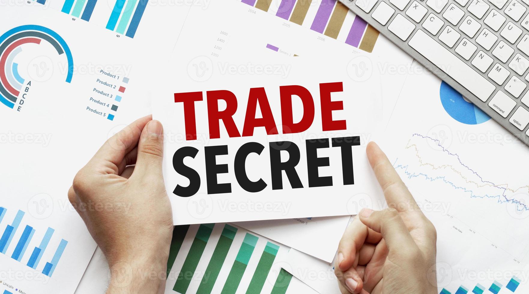 Businessman holding a card with text trade secret .Keyboard, diagram and white background photo