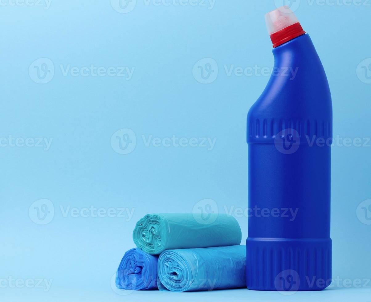 Garbage bags and a blue bottle with detergent on a blue background photo