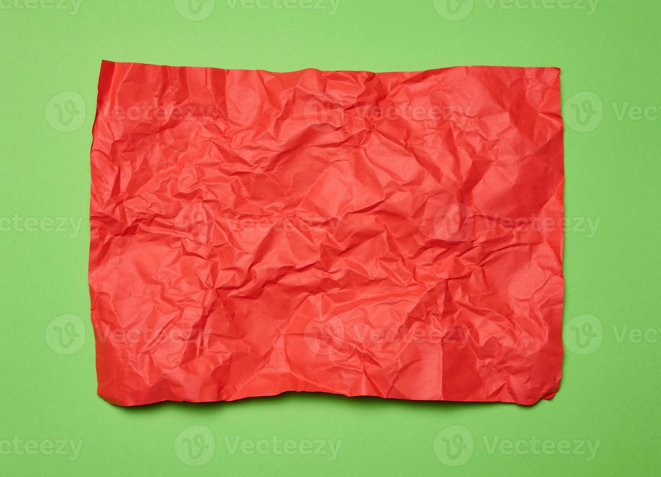 estropeado rectangular sábana de rojo papel en un verde fondo, parte superior vista. sitio para inscripción foto