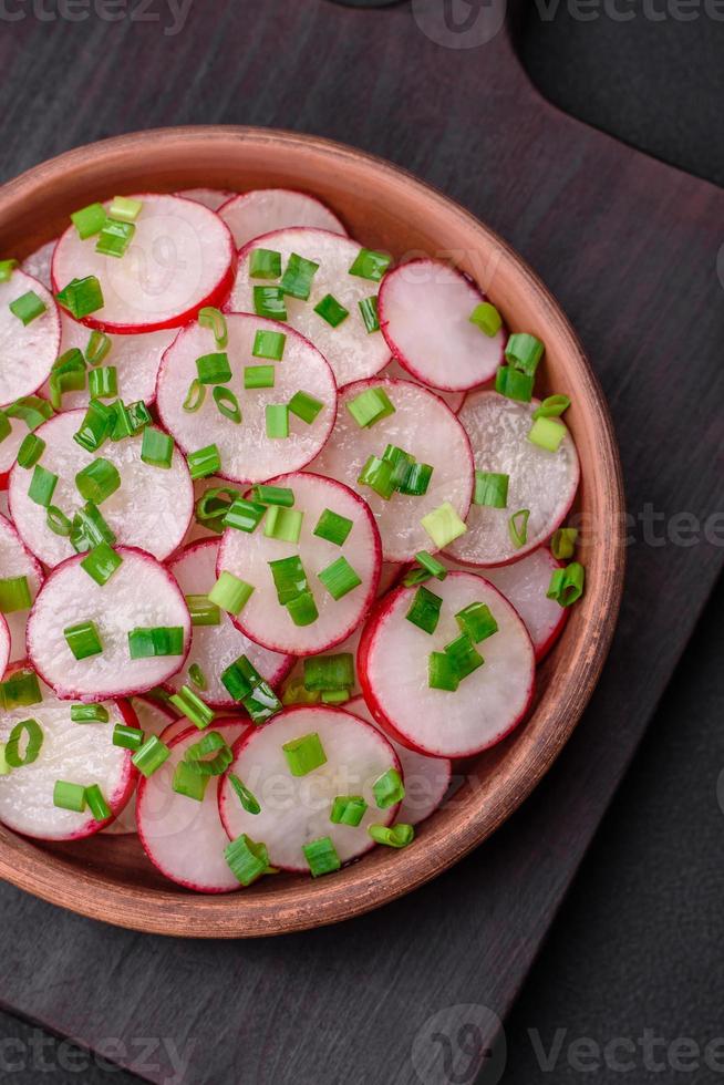 Delicious fresh salad of sliced radishes with green onions, salt and olive oil photo