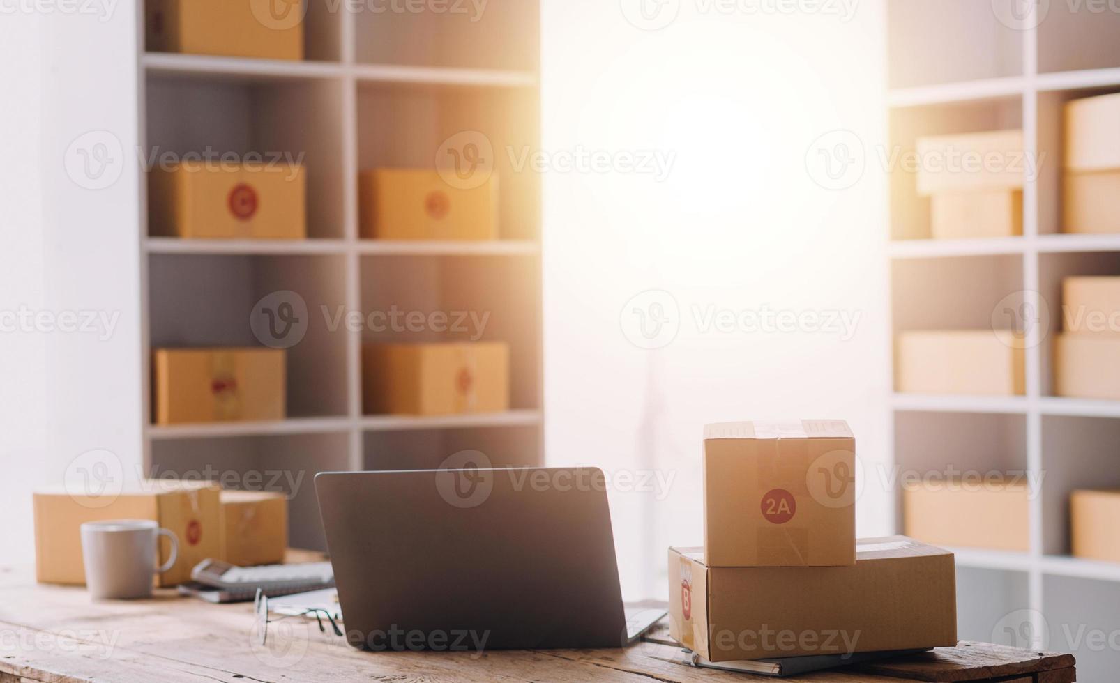 Startup SME small business entrepreneur of freelance Asian woman using a laptop with box Cheerful success Asian woman her hand lifts up online marketing packaging box and delivery SME idea concept photo