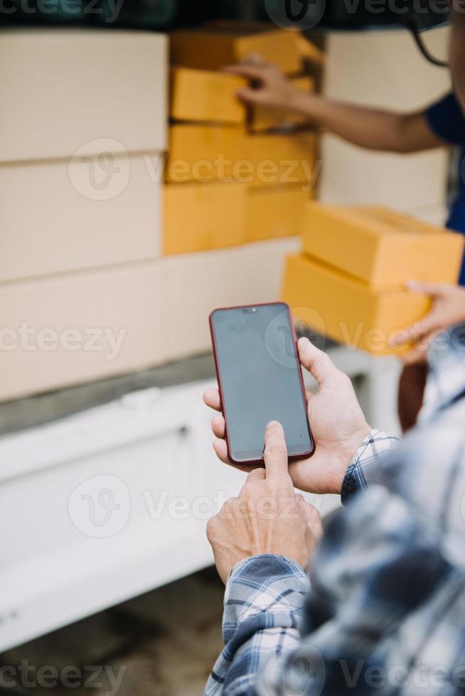 Entrepreneurs Small Business SME Independent men work at home Use smartphones and laptops for commercial checking, online marketing, packing boxes, SME sellers, concept, e-commerce team, online sales photo