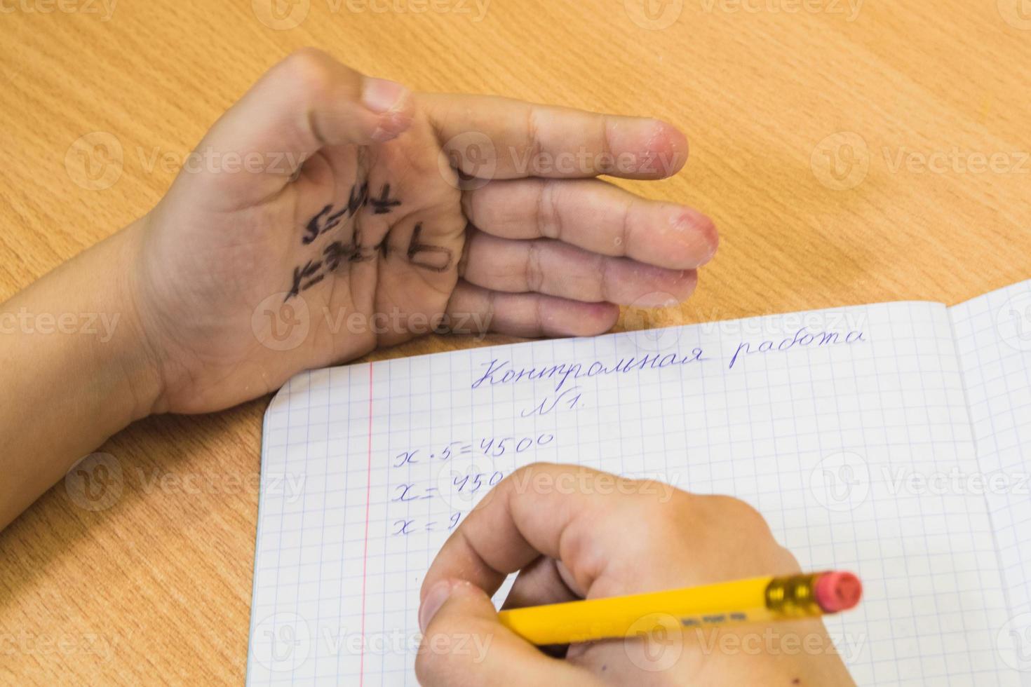 estudiante escribe apagado el prueba desde el engañar sábana escrito en el mano. inscripción en un sábana examen en ruso foto