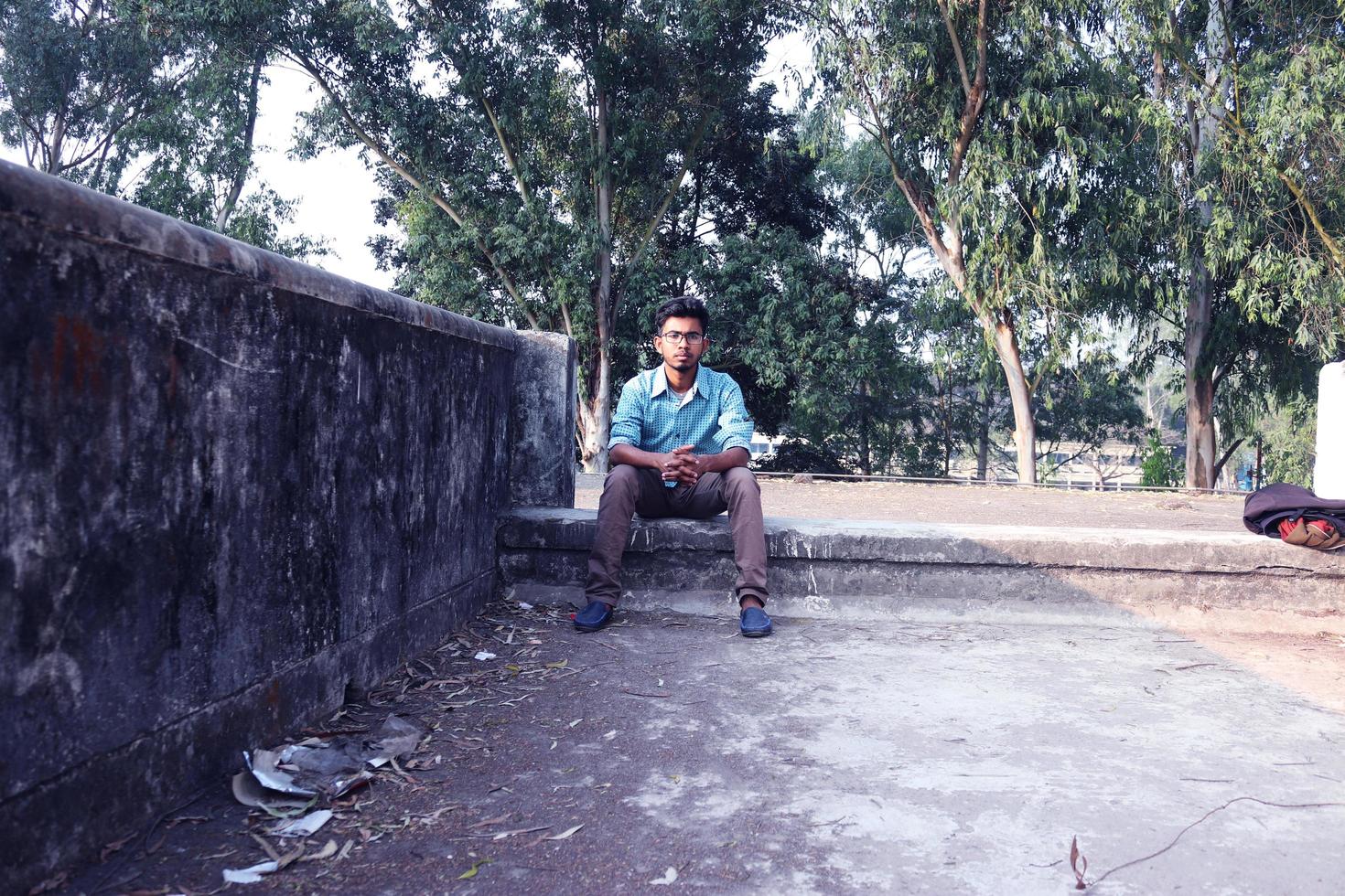 rangpur, Bangladesh 2023. Deprimido adolescente hombre sentado solo en pared en exterior.desagradable dolor. triste infeliz hermoso hombre.bangladeshi y Asia chico sufrimiento depresión. foto