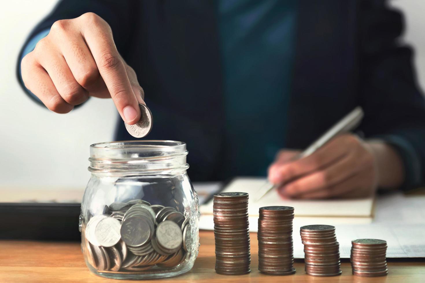 close up hand putting coins in to jug glass for save money photo