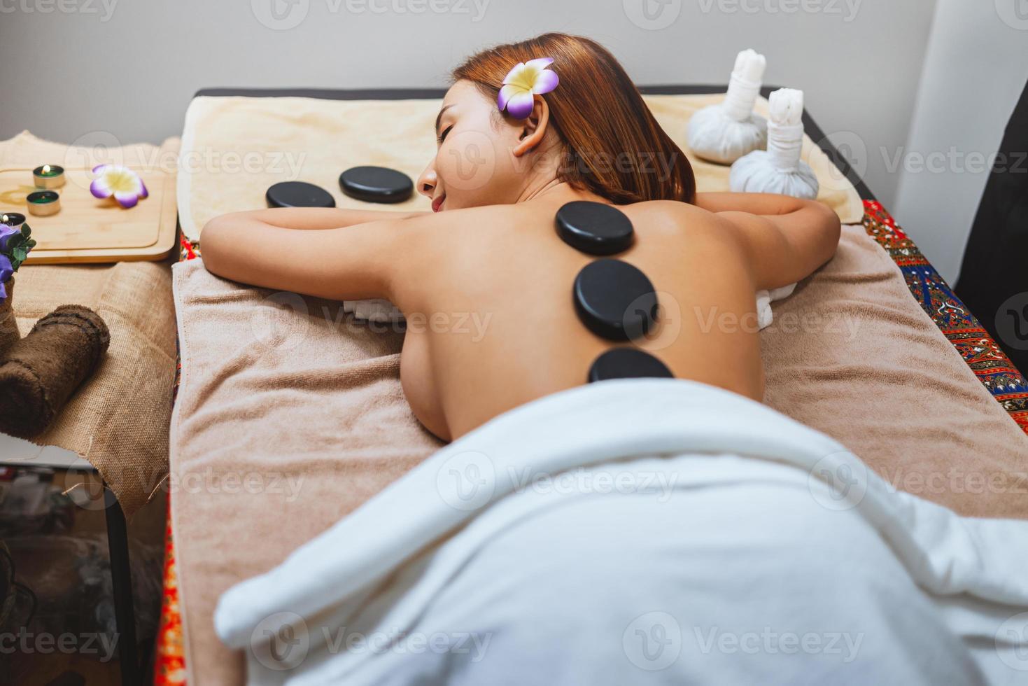 beautiful woman receiving hot stone massage in spa photo