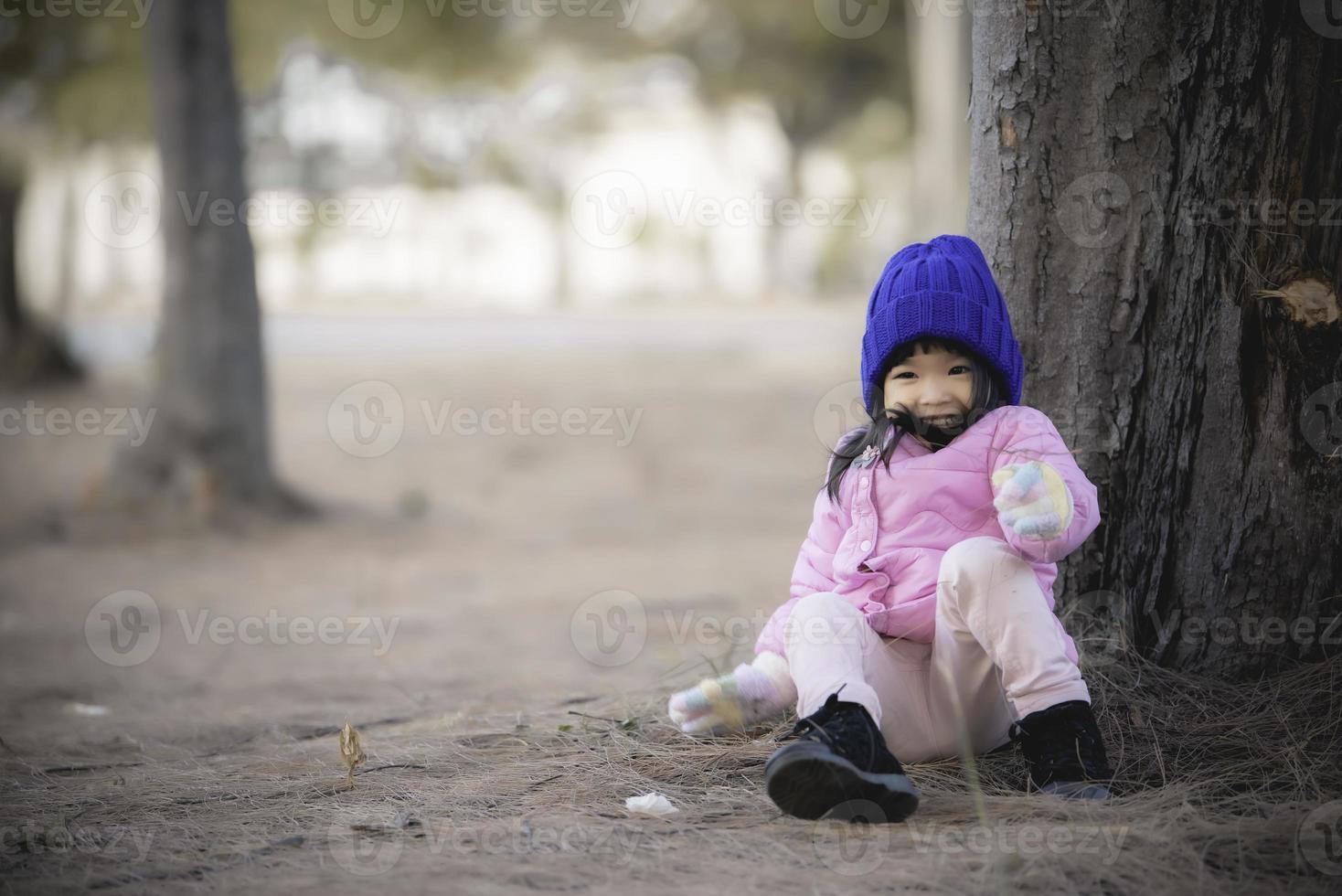 Portrait of cute asian little girl wear Winter clothes at the forest of the park,Thailand people pose for take a picture,Happy time photo