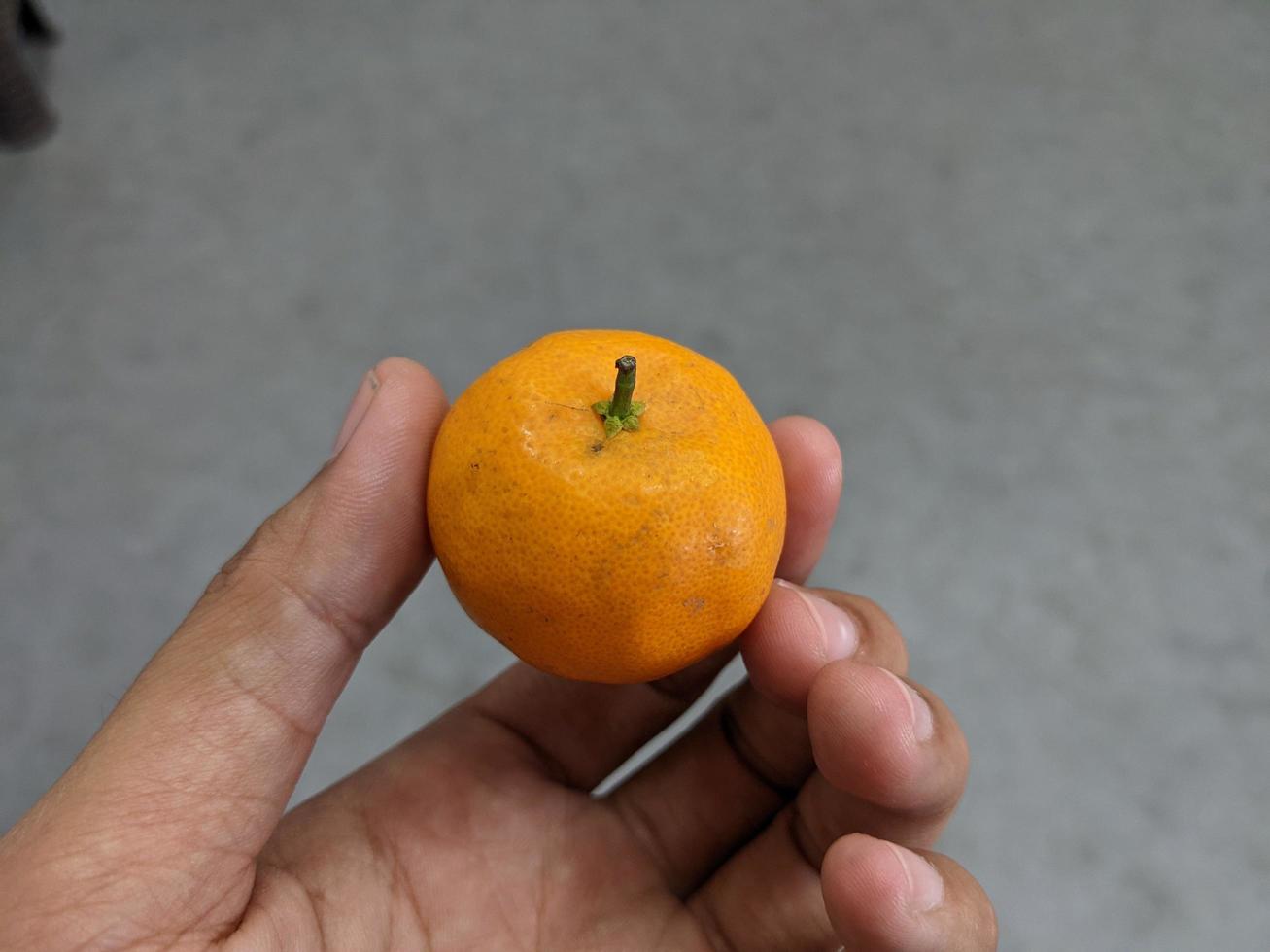 Little orange hold on the bare hand. The photo is suitable to use for fruit background and seller advertising.