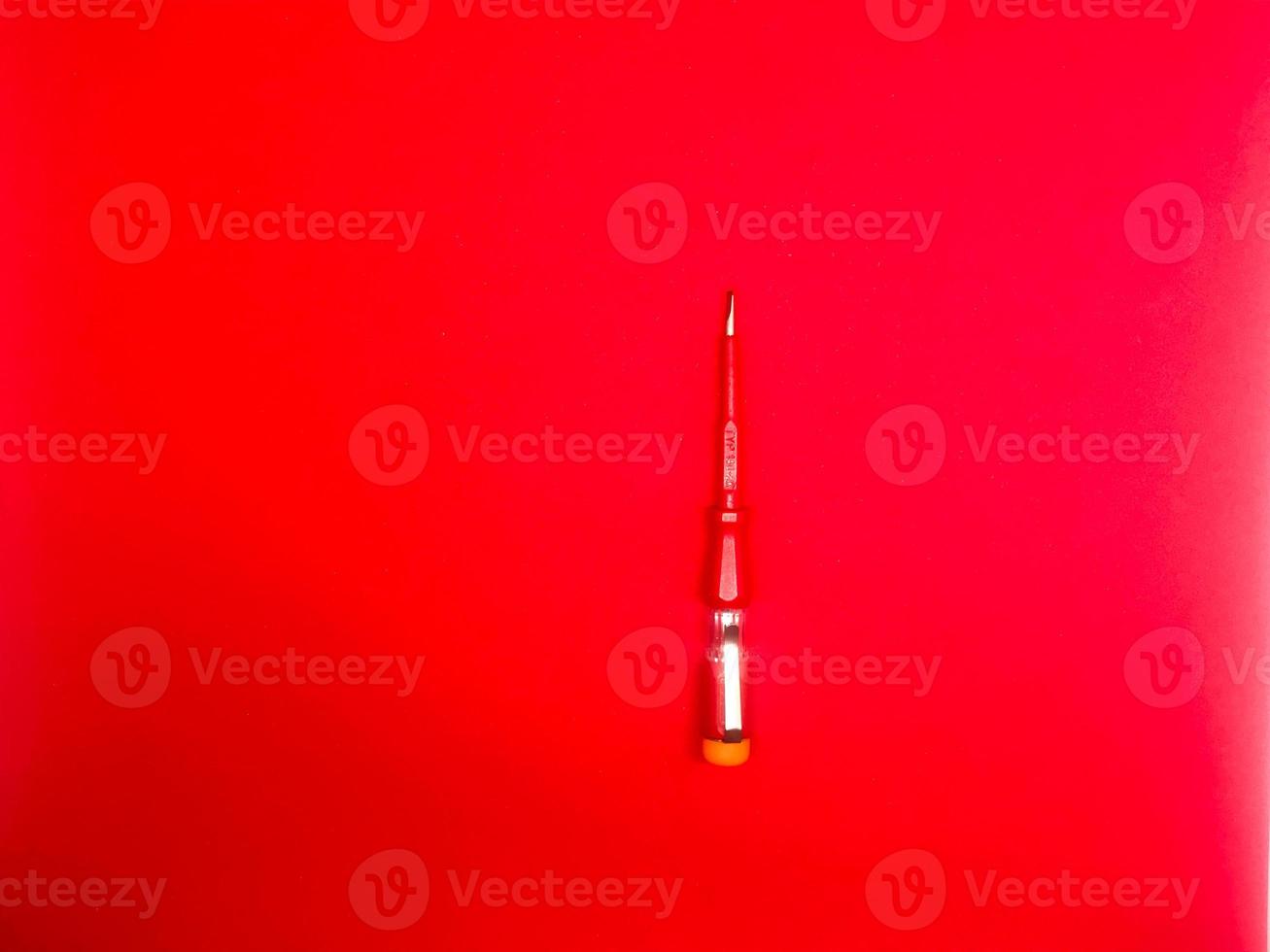 red screwdriver insulated with red background photo