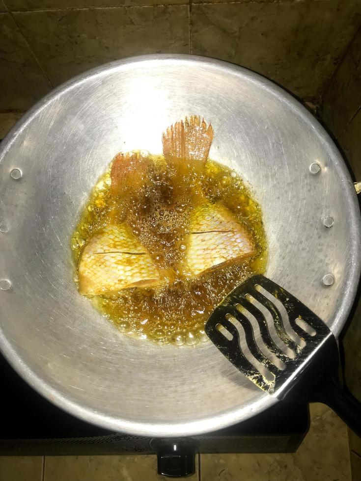 pescado ese es siendo frito utilizando petróleo en un Cocinando maceta foto