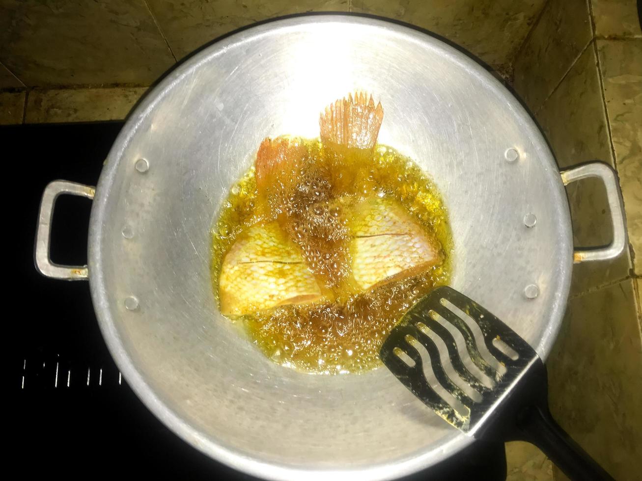 fish that is being fried using oil in a cooking pot photo