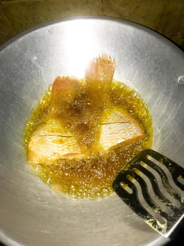 pescado ese es siendo frito utilizando petróleo en un Cocinando maceta foto