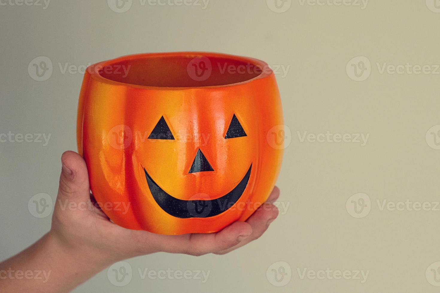 beautiful  orange flower pot pumpkin for halloween on a light background held in a child's hand photo